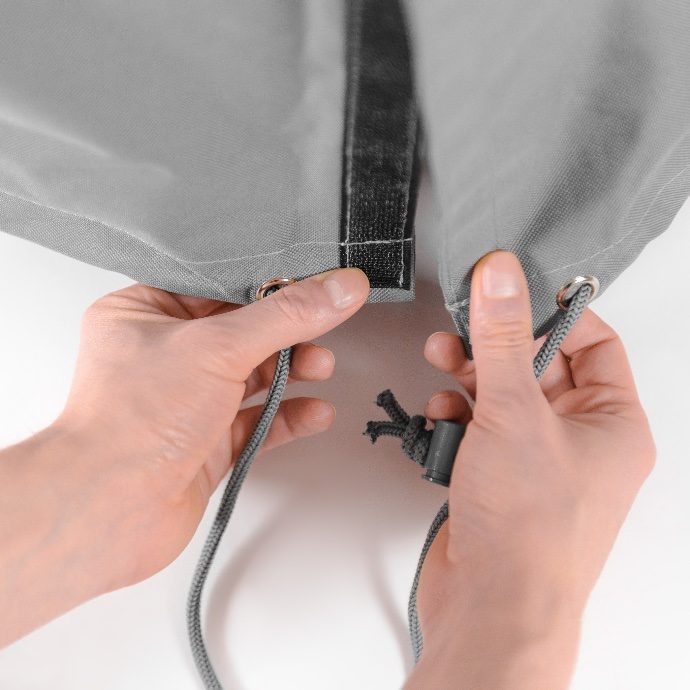 Hands fitting a protective cover on a commercial patio heater during maintenance